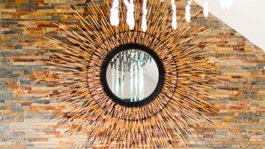 A fireplace with a TV screen, a mirror with a sunburst design, and a hanging light fixture.