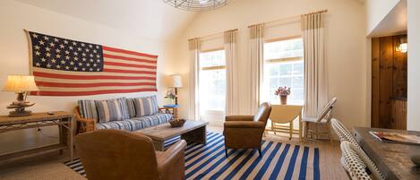 A living room with a large American flag, a sofa, a coffee table, a chair, and a striped rug.