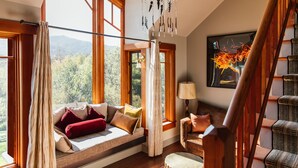 A cozy room with a large window seat, a chandelier, and a painting on the wall. - Olema House at Point Reyes (Olema)