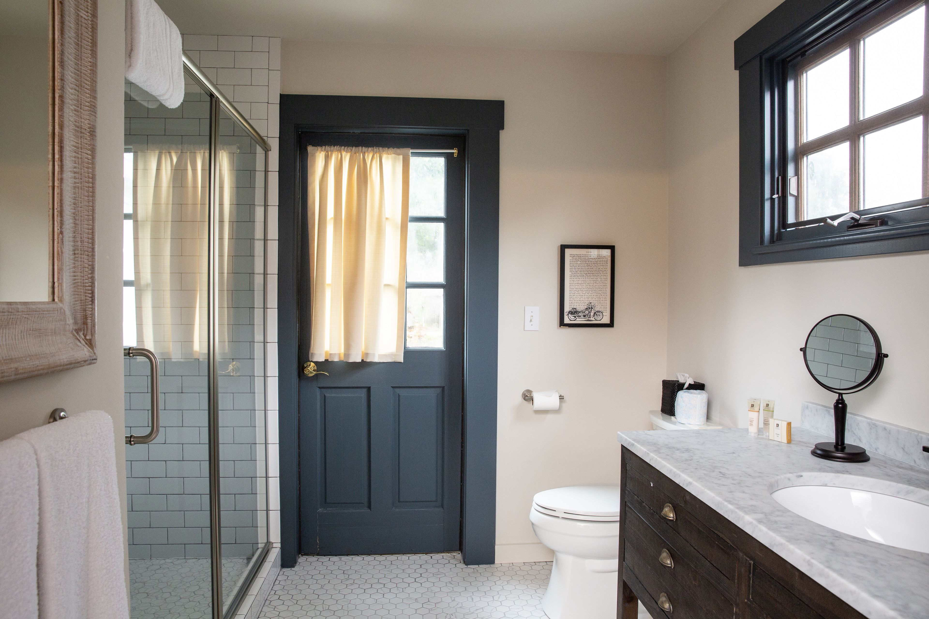 A bathroom with a shower, toilet, sink, and a door with a curtain.