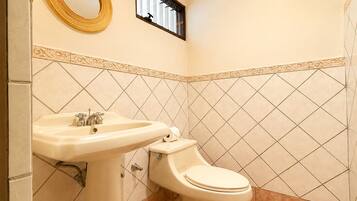 A bathroom with a sink, toilet, decorative mirror, and patterned tiles.