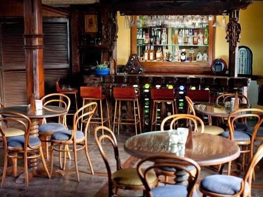 A bar area with wooden furniture and a bar counter stocked with bottles.