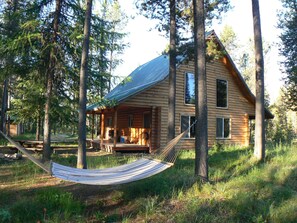 A log cabin with a porch and a hammock.