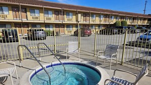 A hotel with a swimming pool, outdoor seating, and a parking lot. - Fullerton Inn - Near Medieval Times (Fullerton)