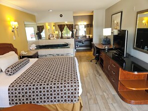A hotel room with a bed, a desk, a TV, and a bathroom with a bathtub.