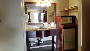 A compact bathroom with a sink, mirror, and a small refrigerator. - Fullerton Inn - Near Medieval Times (Fullerton)