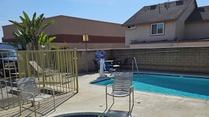 A swimming pool with a small hot tub, surrounded by lounge chairs and a fence. - Fullerton Inn - Near Medieval Times (Fullerton)