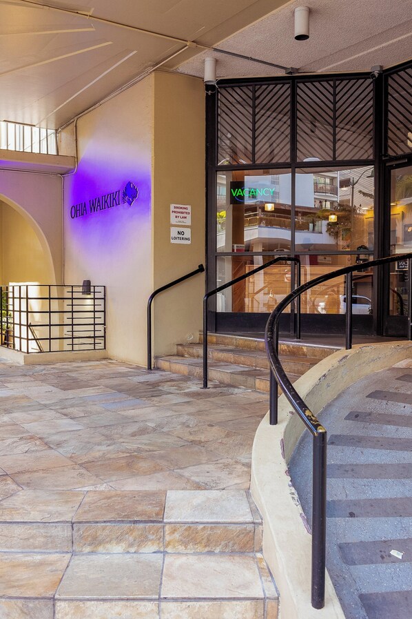 A hotel entrance with a sign indicating 'Vacancy' and a 'No Loitering' sign.