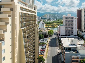 A high-rise building with multiple balconies, a parking lot, and a river in the background. - Ohia Waikiki Studio Suites (Honolulu)