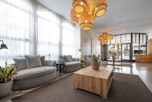 A modern living room with a grey sofa, wooden coffee table, and potted plants.