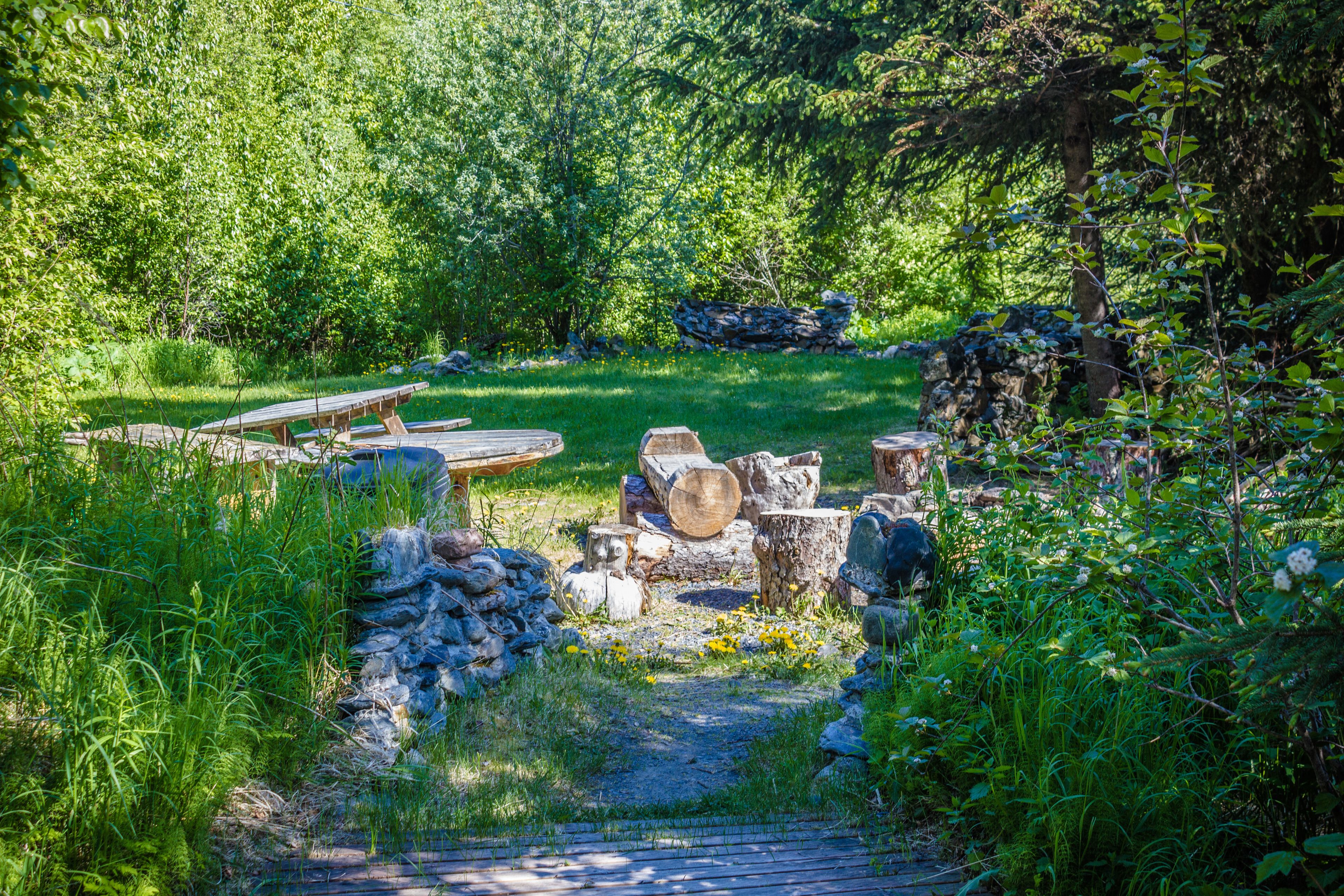 Un espace extérieur rustique doté d’une terrasse en bois, d’éléments en pierre et d’une végétation luxuriante.