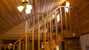 Un escalier en bois, un ventilateur de plafond, une fenêtre avec vue et une chaise dans la pièce.