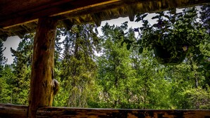 Une structure rustique en bois, offrant une vue sur un feuillage verdoyant et dense, avec des arbres en arrière-plan.