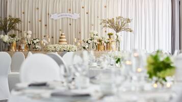 A formal event setup with a stage, floral arrangements, and a banner indicating a 1st birthday party.