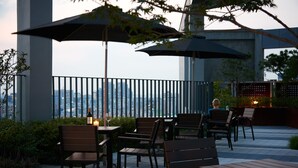 An outdoor patio with tables and chairs, umbrellas, and a view of the city skyline. - Hotel Peyto Gangnam (Seoul)
