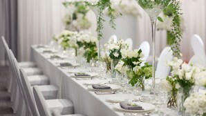 A long banquet table set with white tablecloths, plates, and glasses, adorned with white flowers and greenery. - Hotel Peyto Gangnam (Seoul)