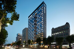 Een modern hotel met een rechthoekige gevel, meerdere verdiepingen en verlichte ramen.