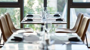 A dining table set for four with chairs, a pitcher, and glasses, positioned near large windows with a view of greenery. - Hotel Peyto Gangnam (Seoul)