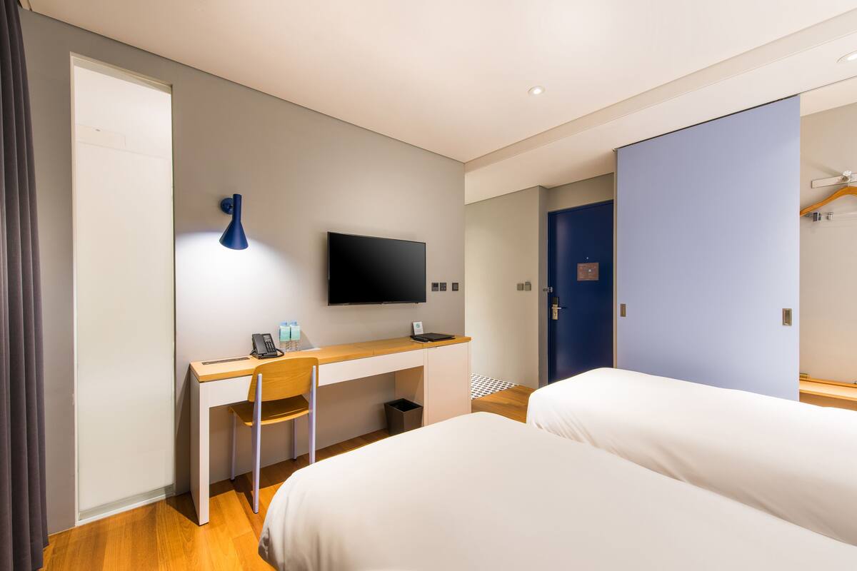 Une chambre d’hôtel avec un lit, un bureau, une télévision et une armoire.