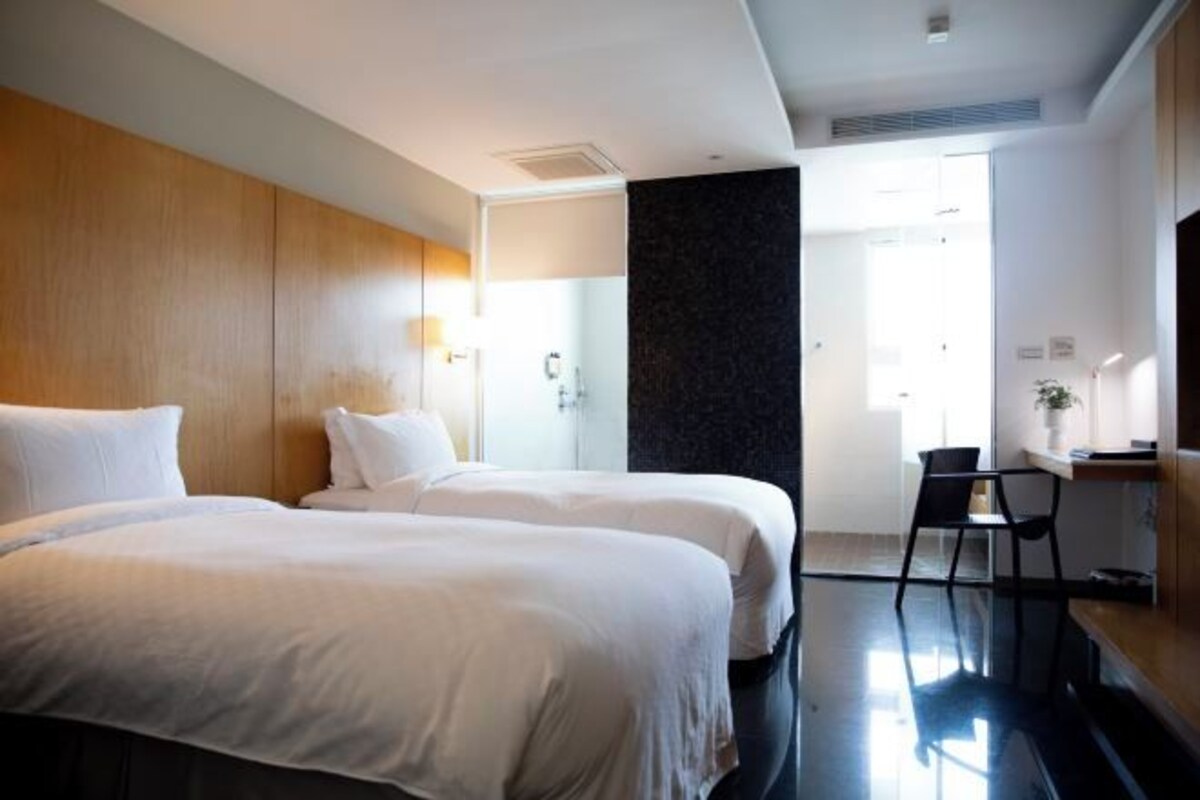 Habitación de hotel con dos camas, un escritorio y una silla.