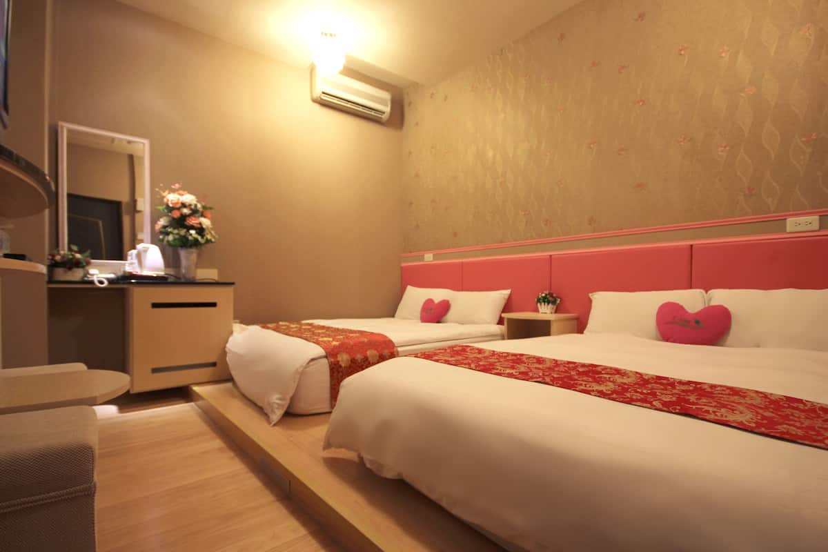 A hotel room with two beds, a desk, and a mirror.