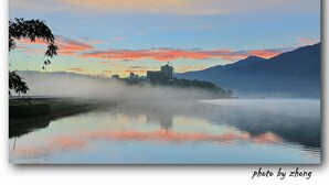 A serene lakeside view with a building in the distance, surrounded by mist and a colorful sky. - Quan Fu Tan Hui Hotel (Yuchi)