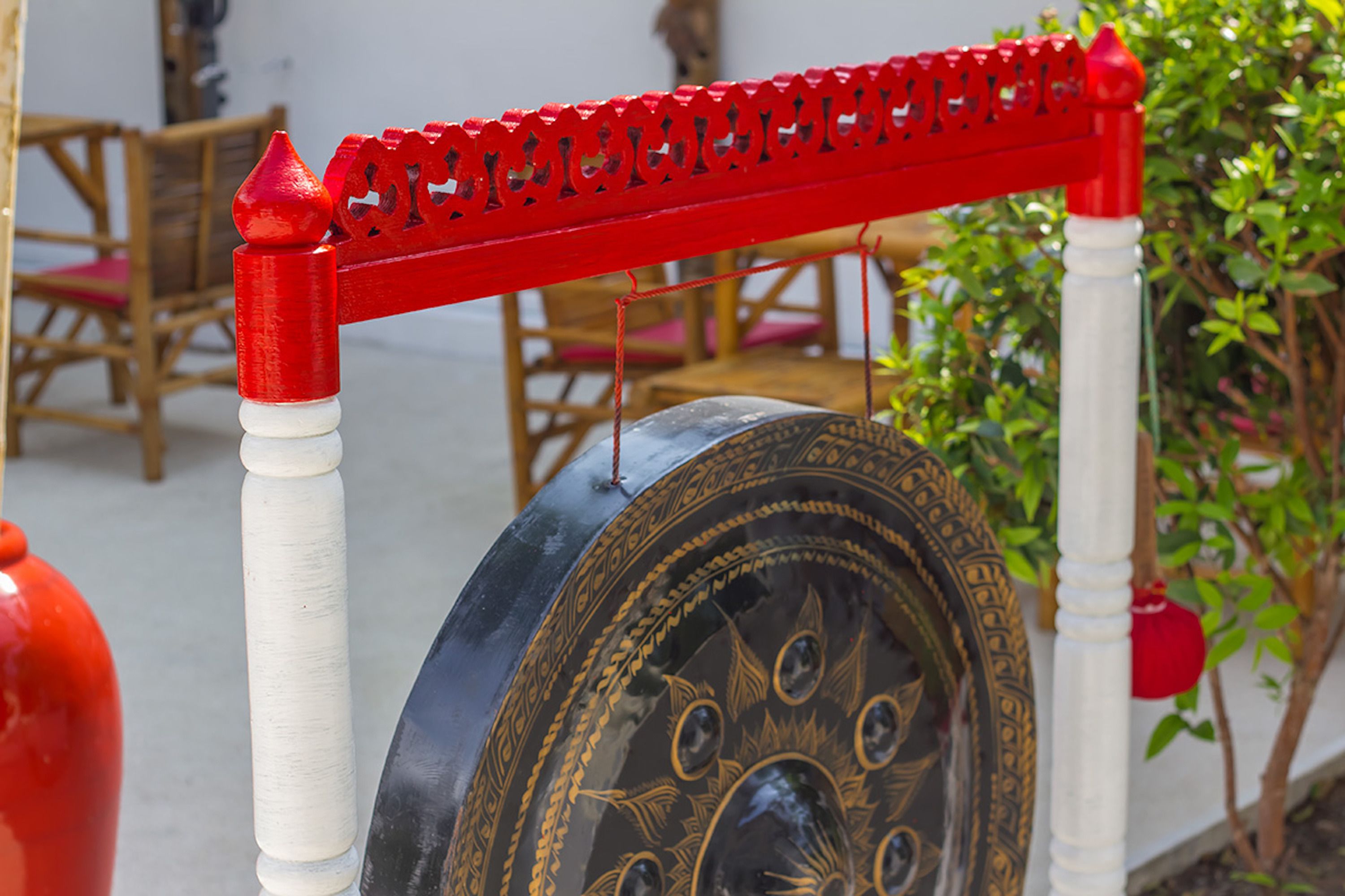 Une porte décorative en métal, ornée de motifs complexes et surmontée d’une barre rouge.
