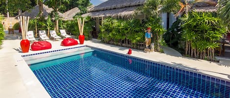 Una piscina al aire libre, sombrillas, sillones reclinables de piscina