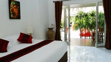 Una habitación de hotel con una cama, un florero y vistas a un jardín a través de una puerta corrediza.