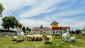 Una fattoria con un cartello che riporta la scritta "THADA CHATEAU" e diverse statue di pecore.