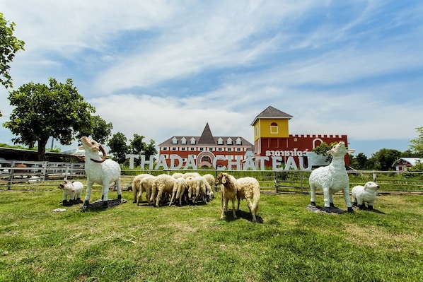 A farm with a sign reading "THADA CHATEAU" and several sheep statues. - Thada Chateau Hotel (Buriram)