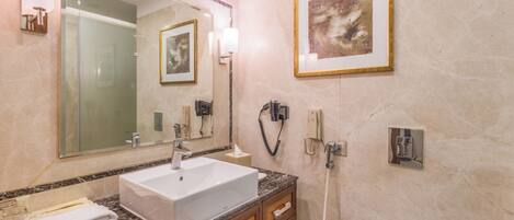 Un baño moderno con un espejo grande, un lavabo blanco, una encimera de mármol y una obra de arte enmarcada en la pared.