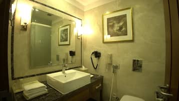 A bathroom with a large mirror, a sink, a toilet, and a framed picture on the wall.
