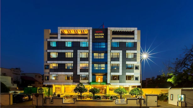 Un hotel de varios pisos con un letrero llamativo que dice "HOTEL GOLDEN MANOR".