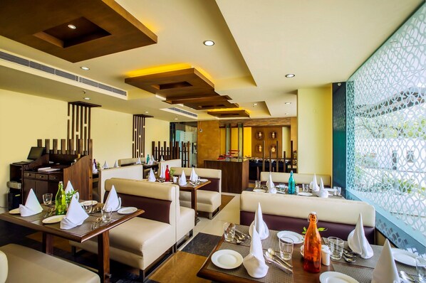 Um restaurante com várias áreas de refeições, incluindo cabines e mesas, com mesas bem dispostas e vista para o exterior.