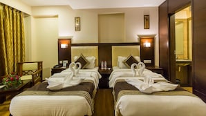 Habitación de hotel con dos camas, cada una con cabecero, mesitas de noche y lámparas. Un espejo en una pared y una ventana con cortinas.