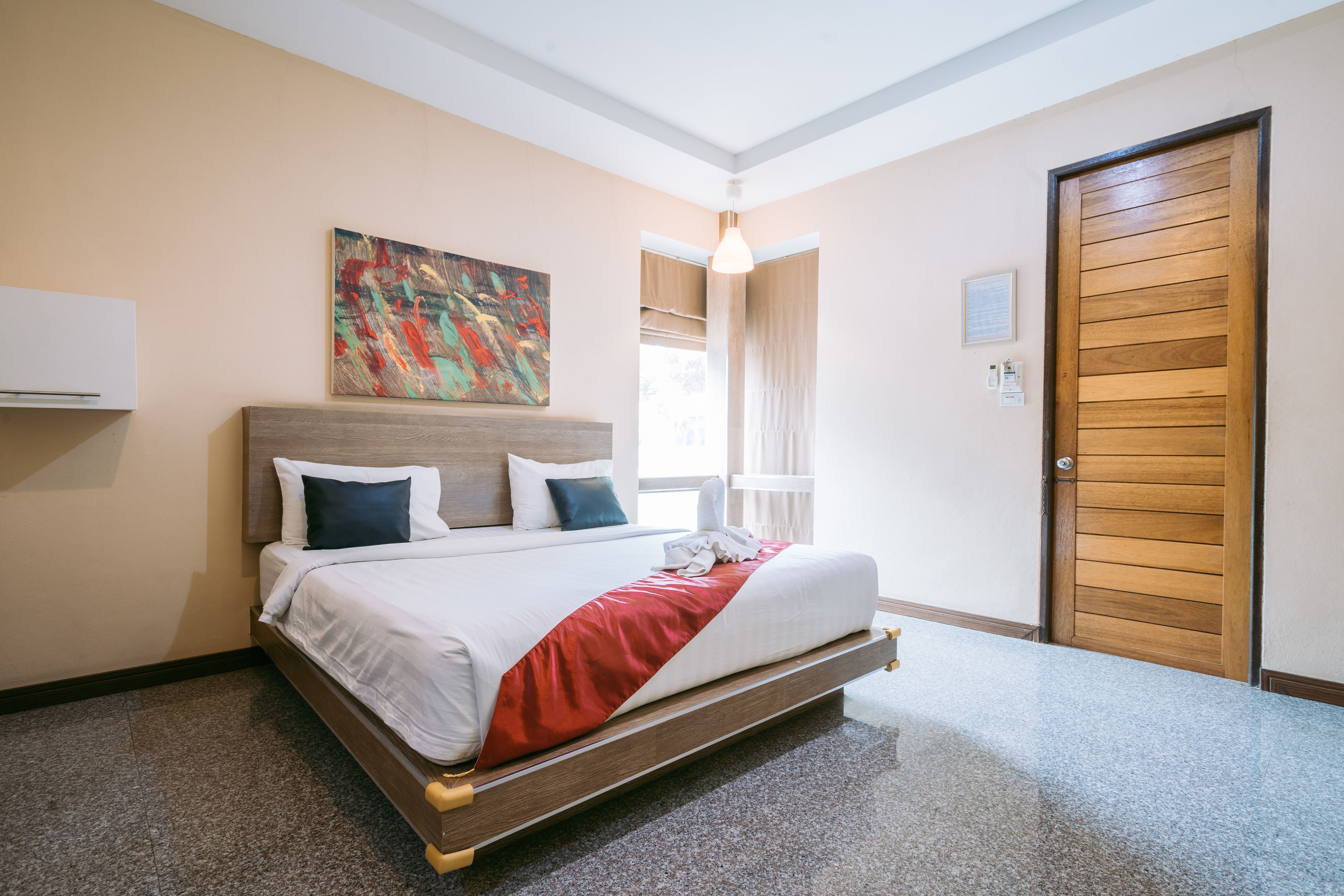 Una habitación de hotel con una cama, un cuadro en la pared, una puerta y una ventana.