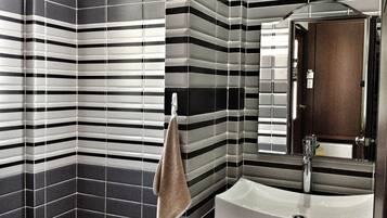 A bathroom with striped tile walls, a sink, and a towel hanging on a rack.