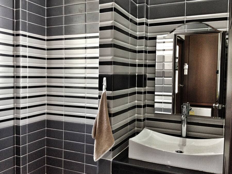 A bathroom with striped tile walls, a sink, and a towel hanging on a rack.