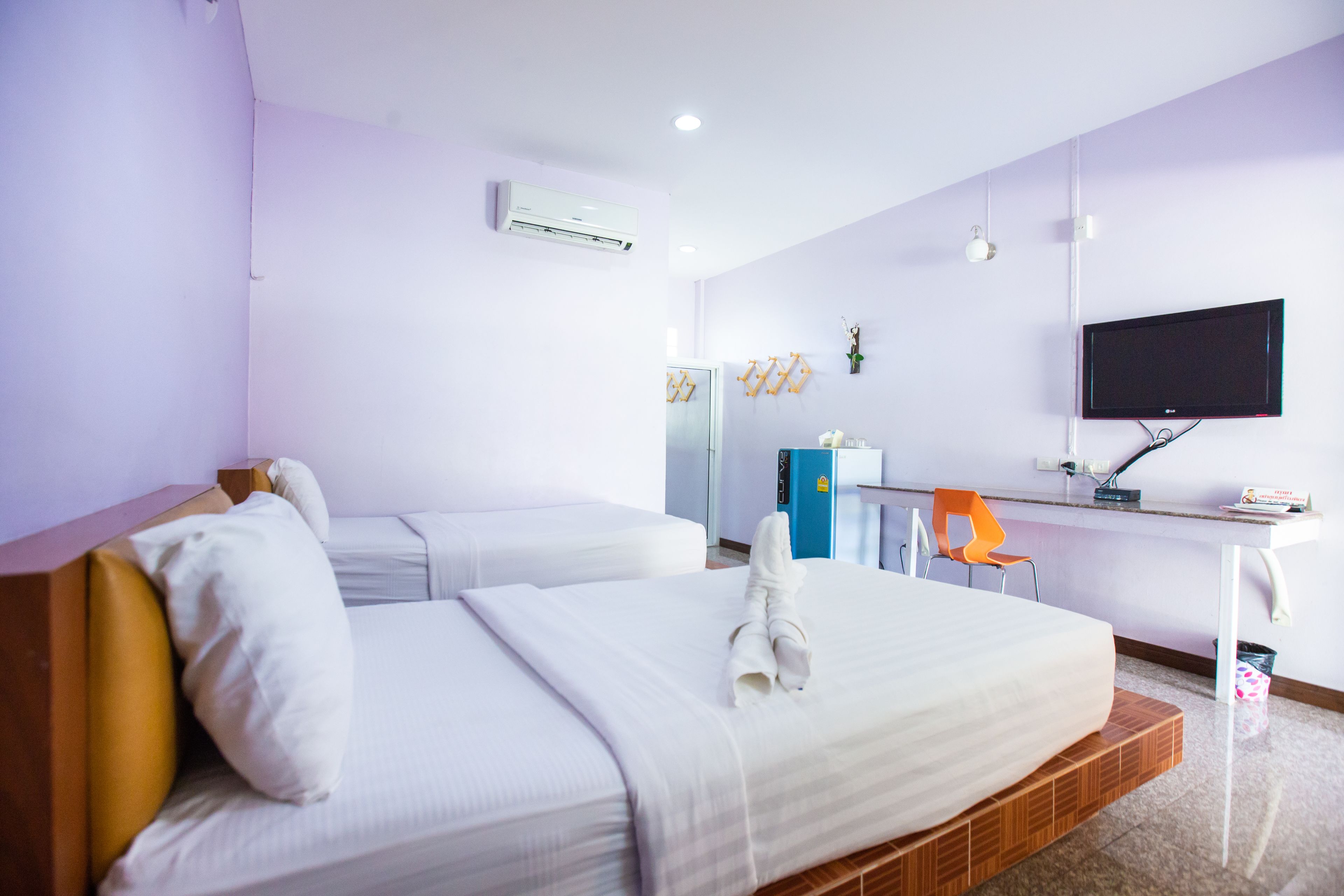A hotel room with two beds, a desk with a TV, and a chair.