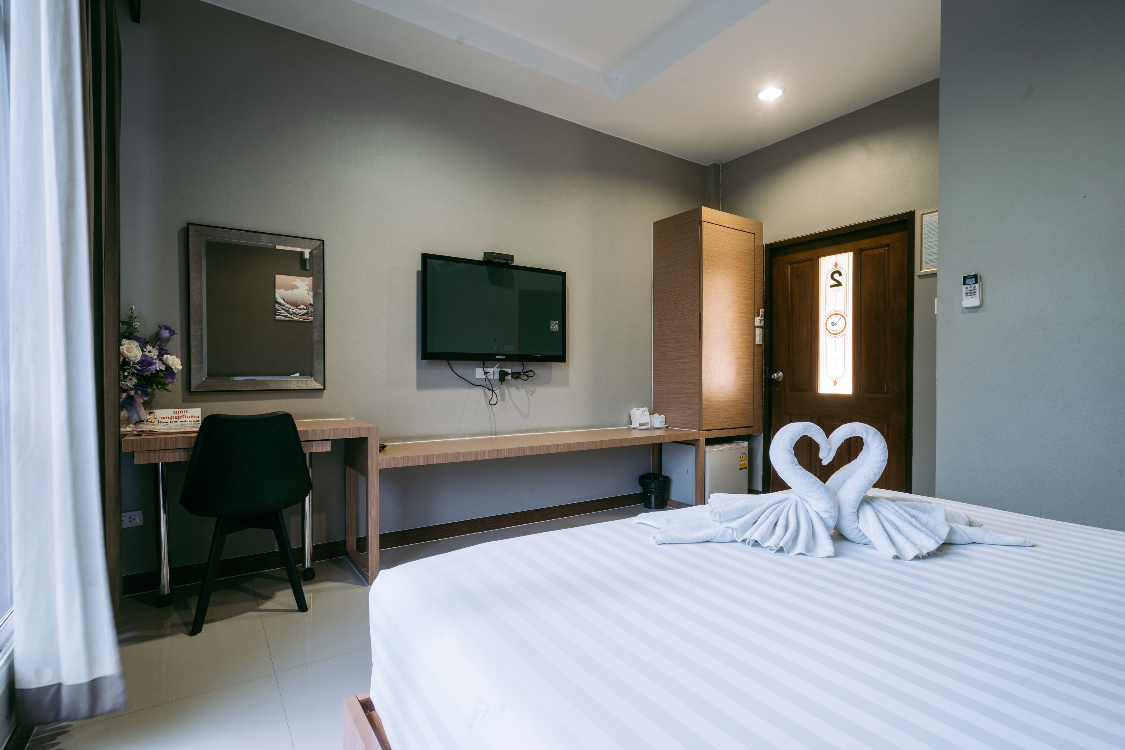 Una habitación de hotel con cama, escritorio, televisión y armario.