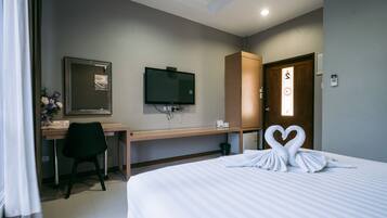 Una habitación de hotel con cama, escritorio, televisión y armario.