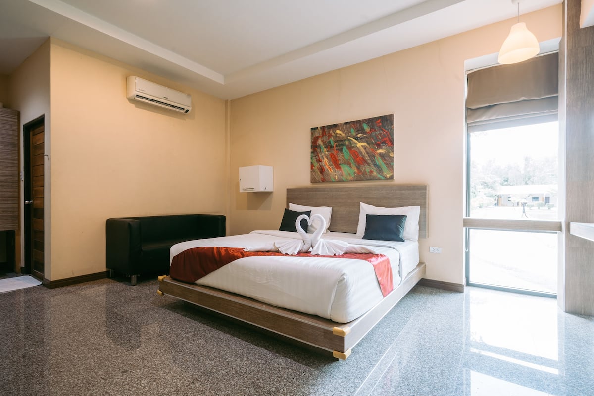 A hotel room with a bed, a painting on the wall, and a window.