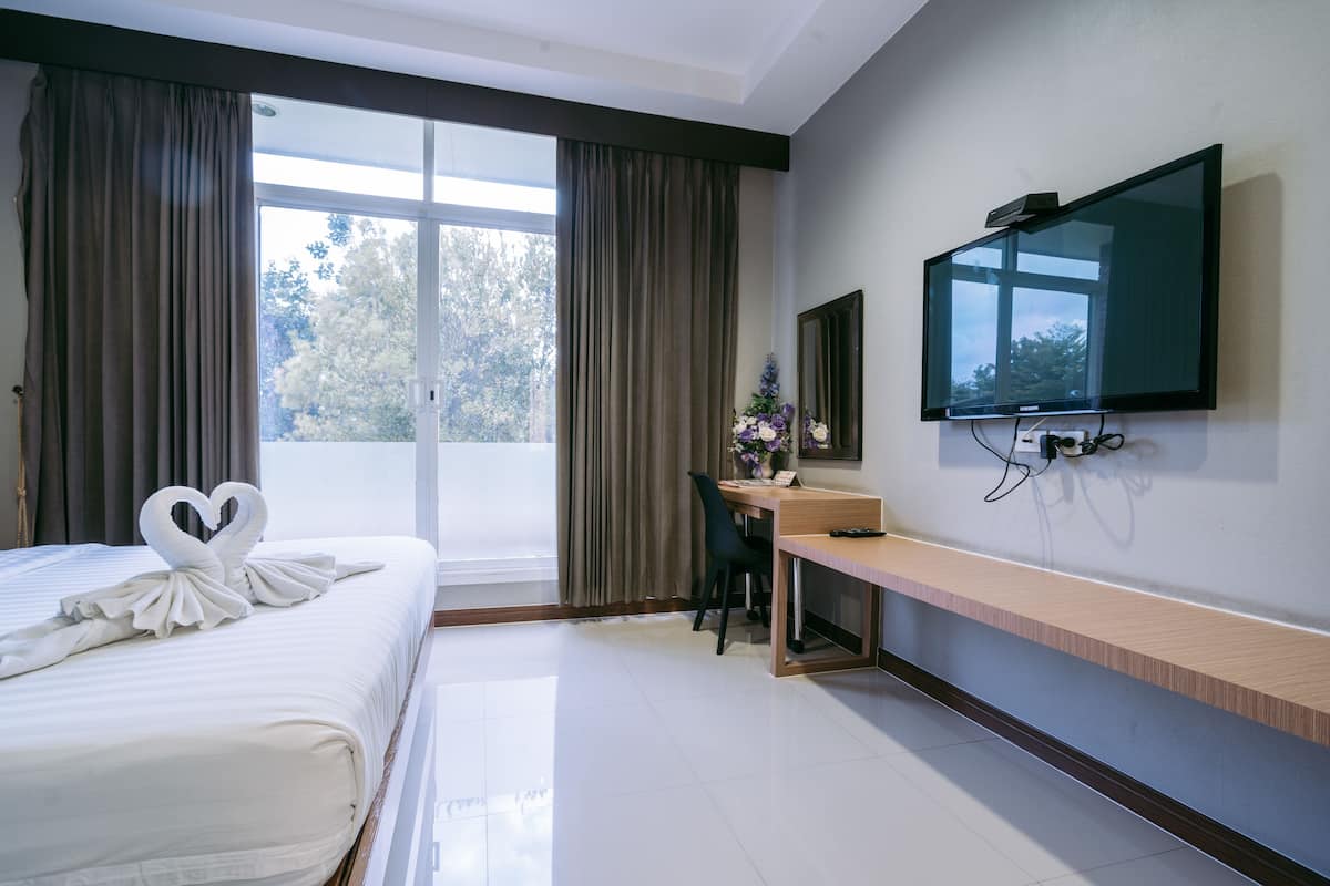 A hotel room with a bed, a desk, a TV, and a window with curtains.