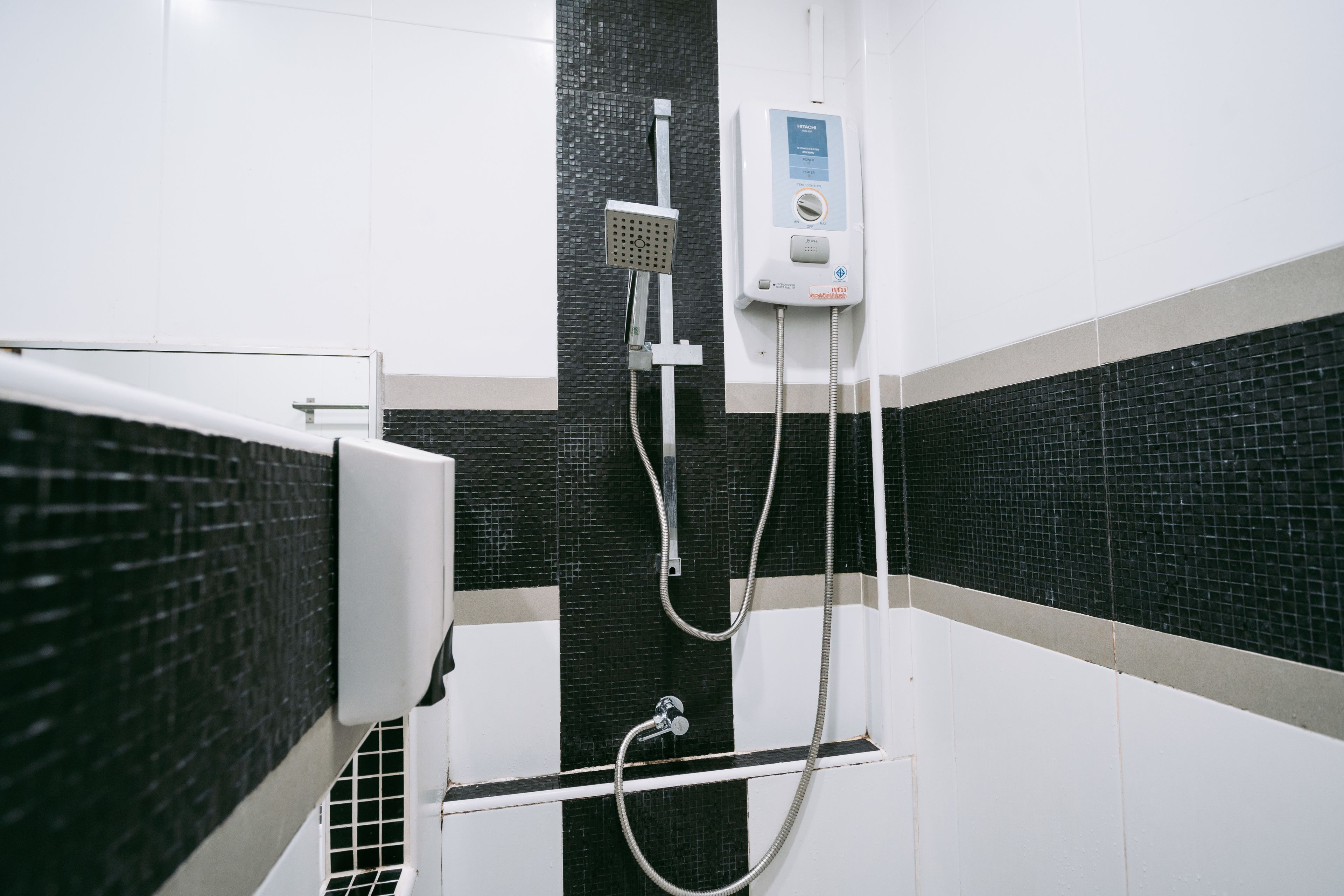 Ein Badezimmer mit schwarz-weißer Fliesenwand, einer weißen Duschkabine und einem Bedienfeld.