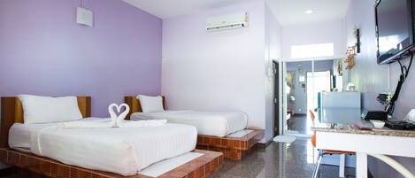 Quarto de hotel com duas camas, televisão e escrivaninha.