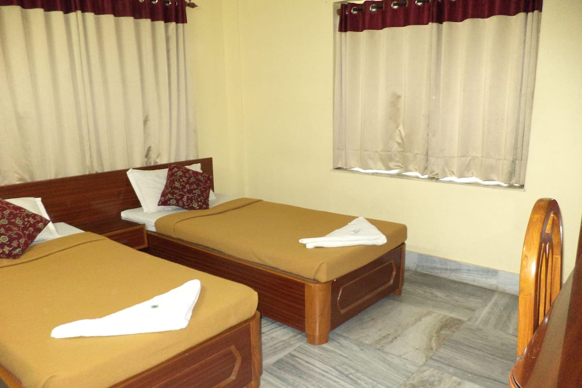 A hotel room with two single beds, wooden headboards, and a marble floor.