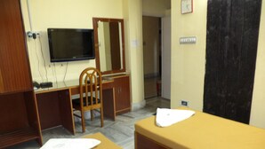 A room with two beds, a desk with a chair, a television, and a mirror. - Simurg- AK50 New Town (Barasat)