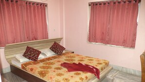 A bedroom with a bed, two pillows, a red blanket, and a floral bedspread. - Simurg- AK50 New Town (Barasat)