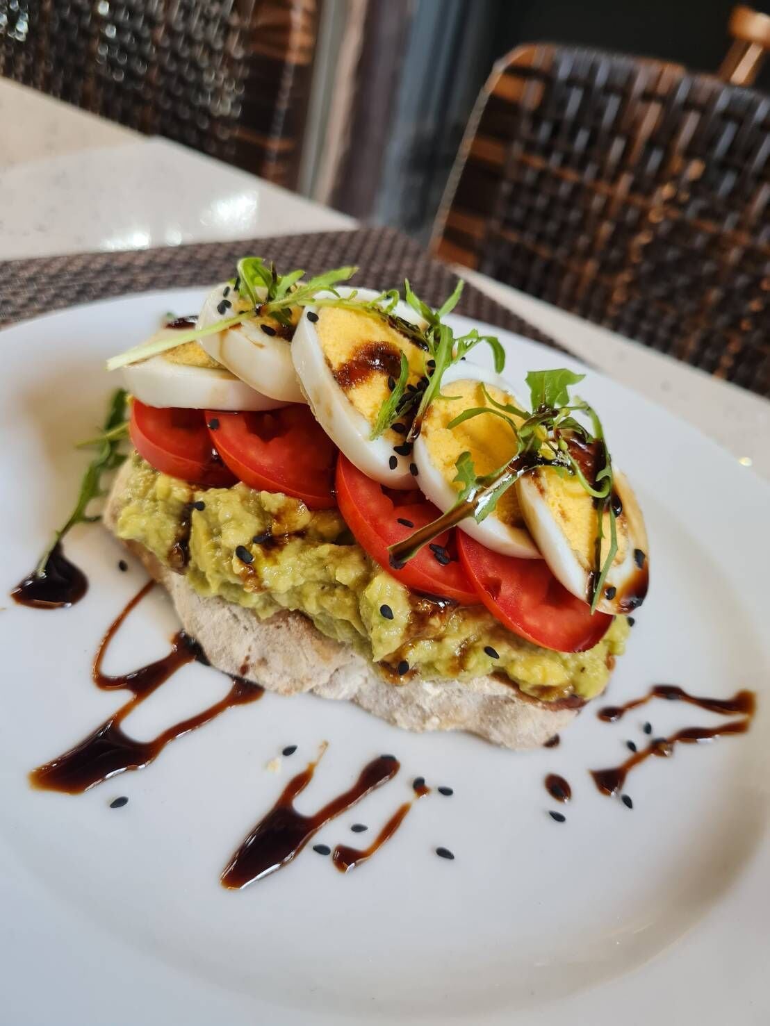 A dish with avocado, tomatoes, and eggs on a white plate.